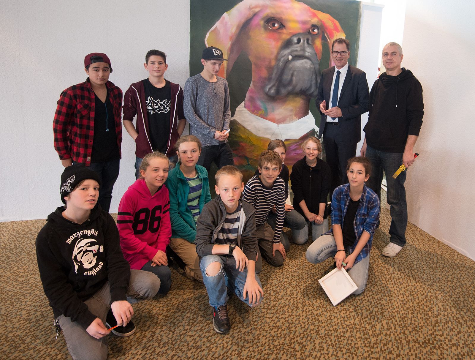 Gruppe von Jugendlichen und Künstler*innen vor einem großen Wandbild